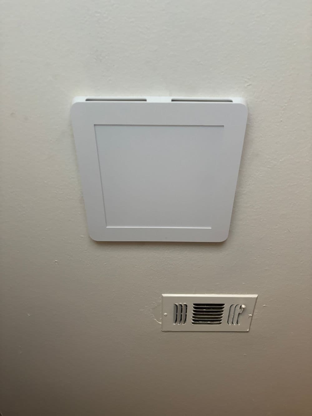 Ceiling-mounted vent cover with rectangular design above a wall vent grille.