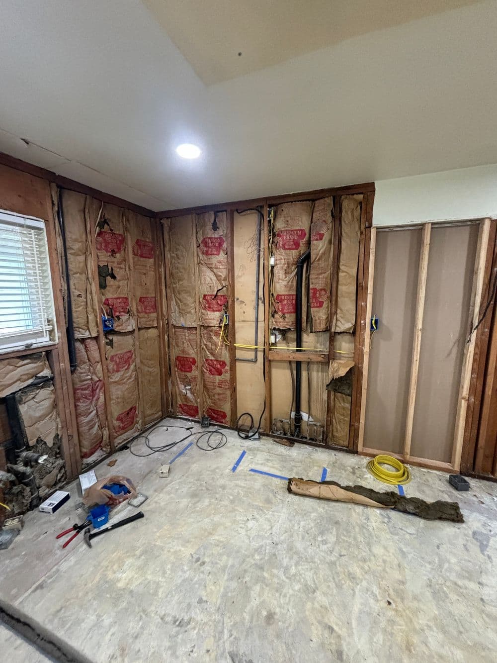 Renovation in progress with exposed insulation, wires, and unfinished walls in a room.