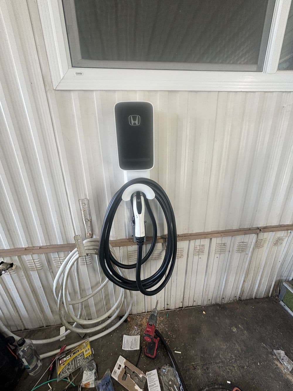 Honda electric vehicle charging station mounted on a wall with a coiled charging cable.