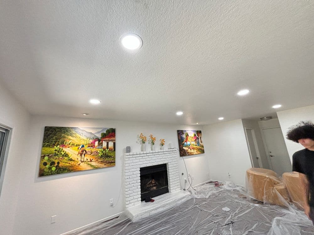 Brightly lit living room with white brick fireplace and colorful artwork on the walls.