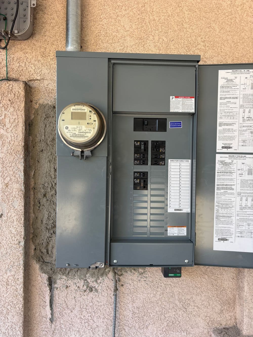Electric meter and circuit breaker panel mounted on exterior wall.