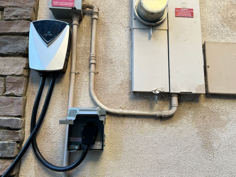 Electric vehicle charging station installed on a wall with power meter and conduit lines.